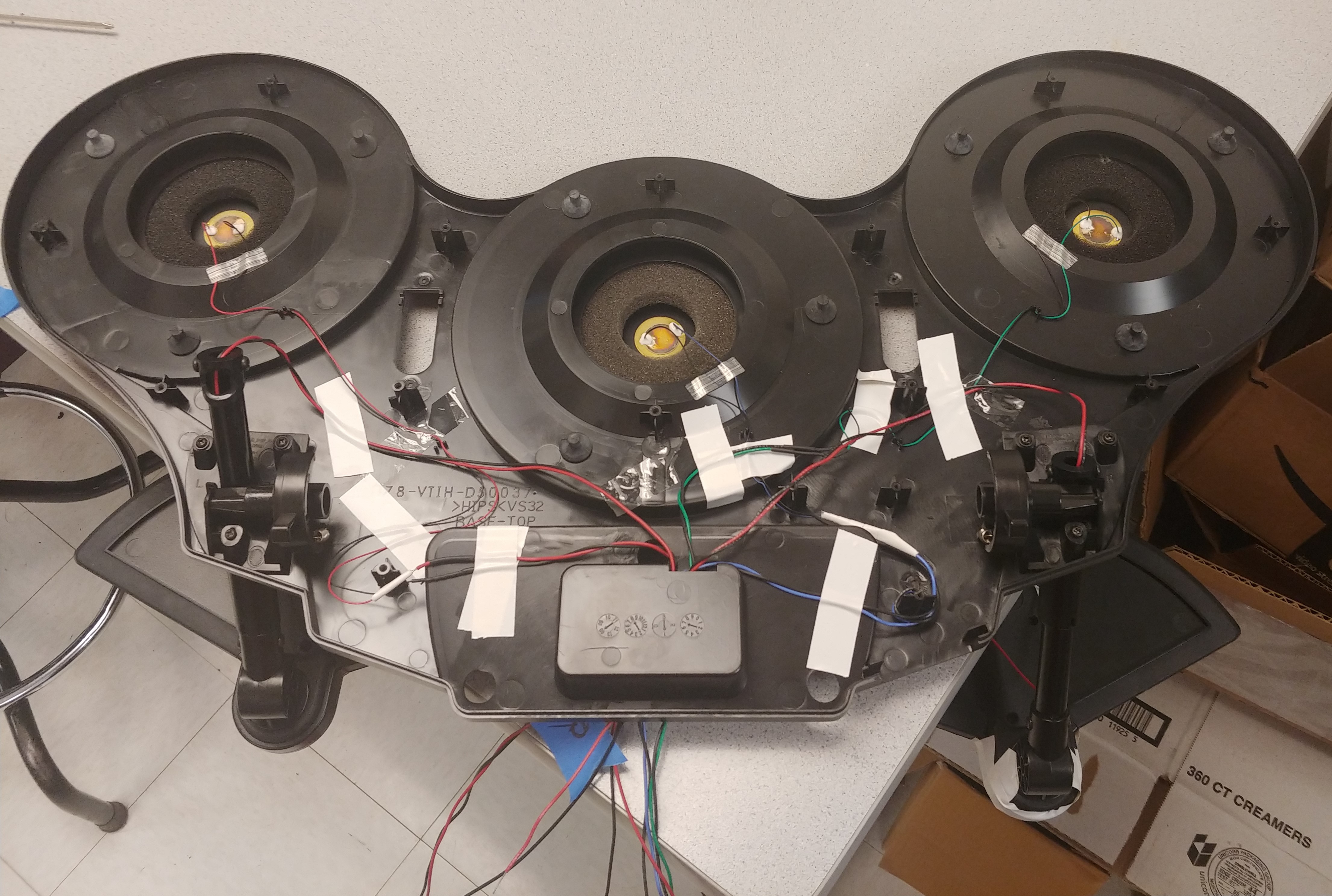 Inside of drum pad chassis with colored wires going from sensors to a hole in the middle